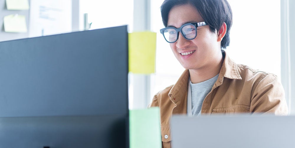 Young graduate male using laptop wearing glasses